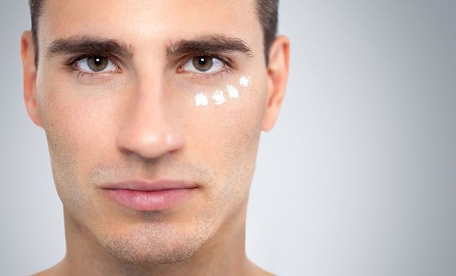 A photo of a man using eye cream. 